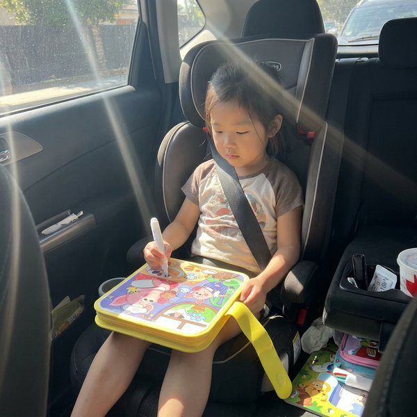 Menina pintando o Aqua Book na cadeirinha do carro