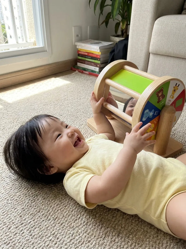 Bebe deitado rindo para o espelho do Tumble Kids