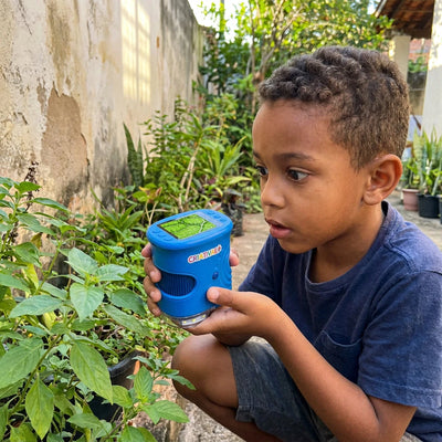 Menino explorando uma folha no quintal com o microscópio infantil Micro Kids Criativaê