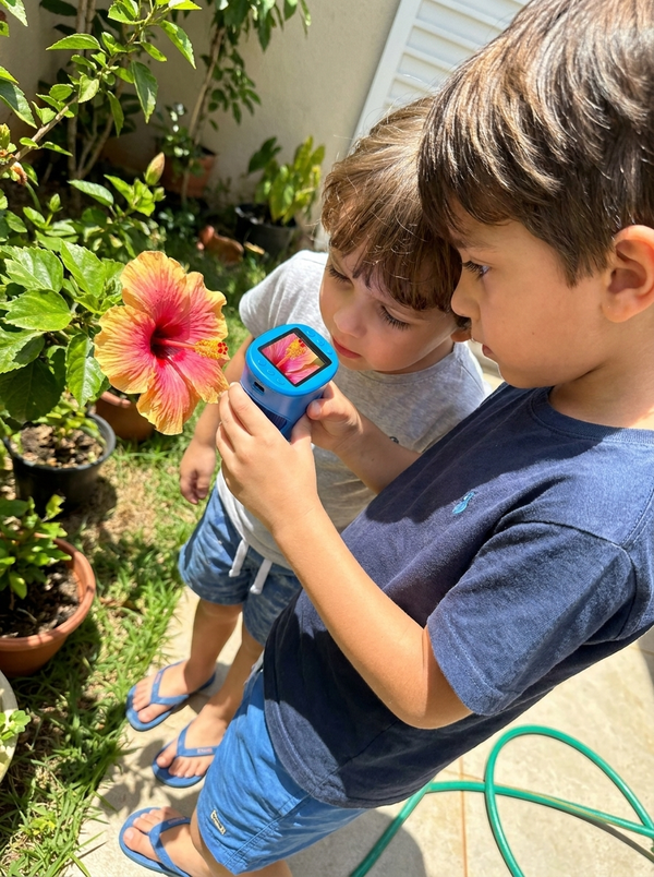 Irmãos observando uma flor no jardim com o Micro Kids