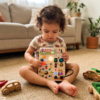 Criança de 2 anos brincando com o painel sensorial Busy Kids no tapete da sala