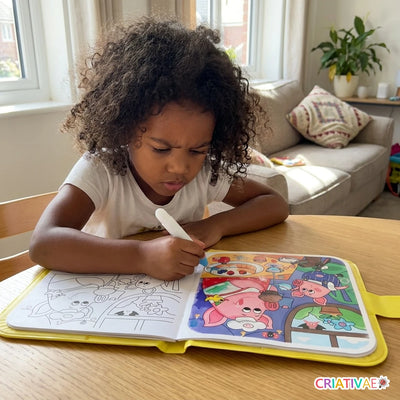Menina pintando com água no livro Aqua Book na mesa de casa
