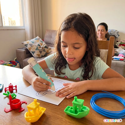 Menina de 7 anos usando a caneta 3D Air Pen para contornar um molde na mesa de casa