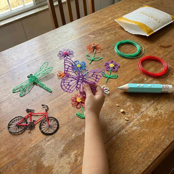 Mesa com pecas 3D feitas com a Air Pen e o envelope Criativae ao fundo