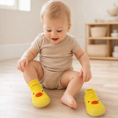 Bebê calçando o Animashoes patinho amarelo sentado no chão de madeira