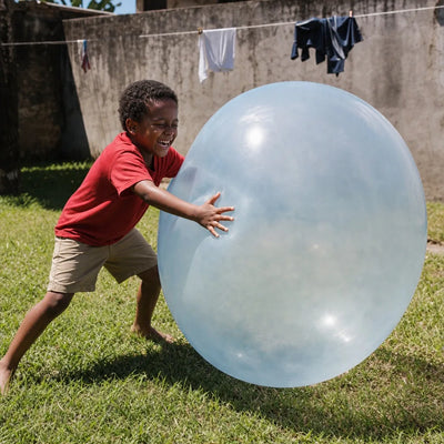Menino brincando no quintal com a bola inflável gigante Gigantball azul